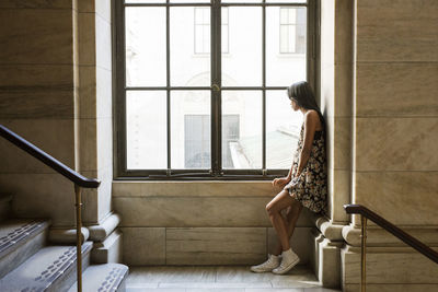 Rear view of woman looking through window