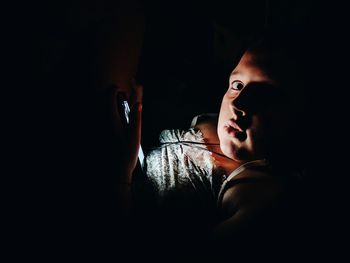 Close-up portrait of woman holding smart phone in darkroom