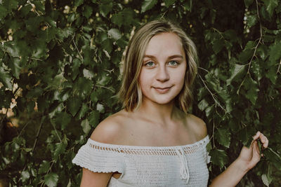 Portrait of smiling young woman standing against plants