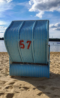Hooded chairs on beach against sky