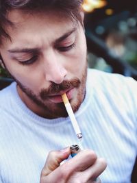 Close-up of man lightning cigarette outdoors