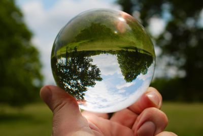 Cropped image of person holding crystal ball in glass