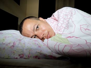 Portrait of man lying on bed at home