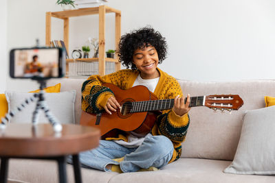 Young woman using laptop while sitting on sofa at home