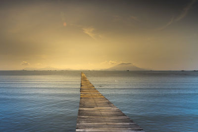 Pier over sea against sky during sunset