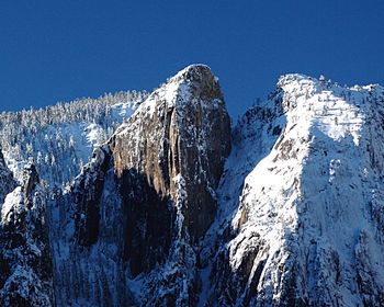 Low angle view of snowcapped mountains against clear blue sky