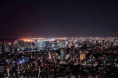 Illuminated cityscape against sky at night