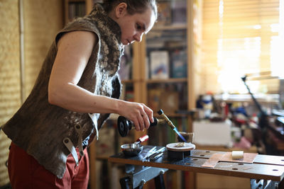 Home workshop girl master roasting on a gas burner in a meta-liter scoop boils water with a copper