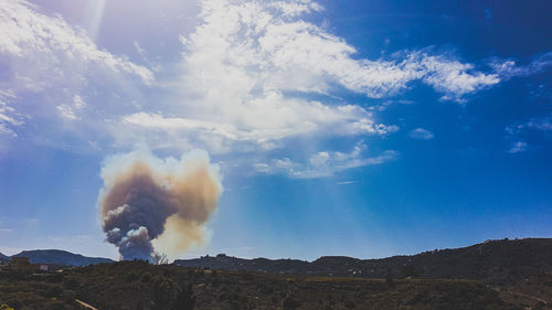 Smoke emitting from mountain against sky