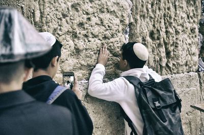 Rear view of people standing against the wall