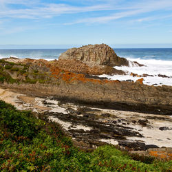 Scenic view of rocks on beach against sky