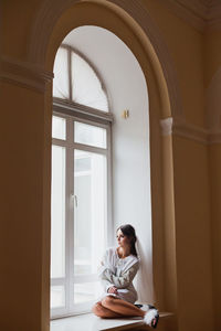 Woman in dress sitting on window sill