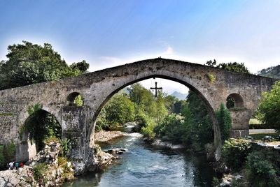 Arch bridge over river against sky