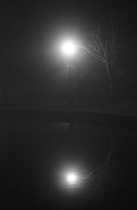 Illuminated street light against sky at night