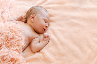 A cute newborn baby sleeps on a fluffy pink bedspread, a healthy and cute baby