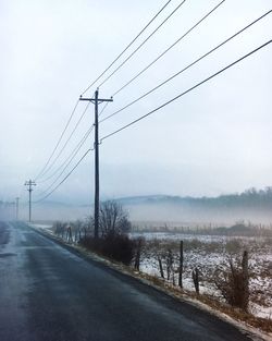 Scenic view of road during foggy weather against sky