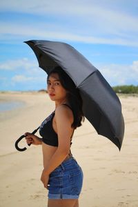 Beautiful woman standing on beach against sky