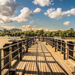 Empty pier over river against sky