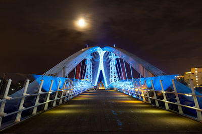 Illuminated footbridge against sky at night