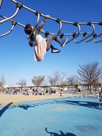 Girl playing on outdoor play equipment in playground