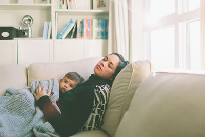 Mother relaxing with son on sofa at home