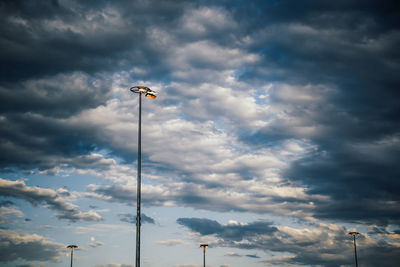 Low angle view of floodlight against cloudy sky