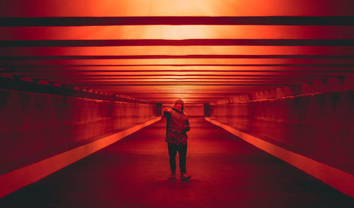 Rear view of woman walking on illuminated corridor