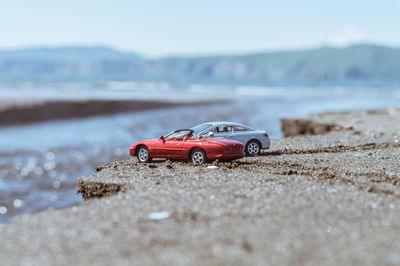 Toy car on beach against sky