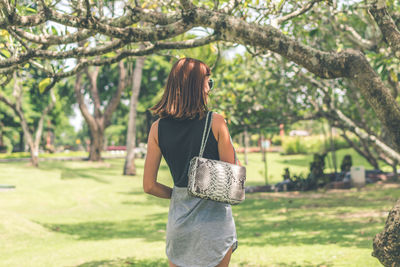 Woman standing by tree against plants