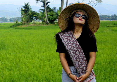 Woman in asian style conical hat standing on field