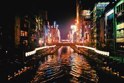 Canal amidst illuminated buildings in city