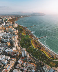 Aerial view of buildings by sea against sky