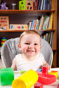 Portrait of cute baby boy playing with toys on table at home