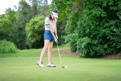 Full length of woman holding umbrella on golf course