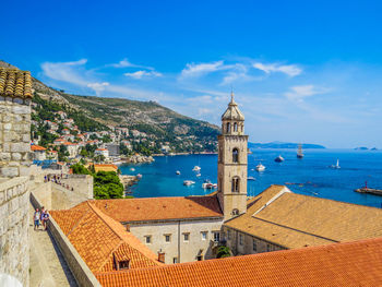 Buildings by sea against blue sky