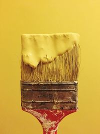 Close-up of yellow paint on brush against wall