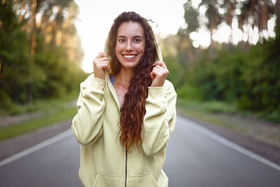 Portrait of smiling young woman standing on road