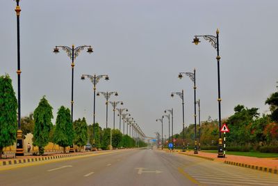 Street lights by road against sky