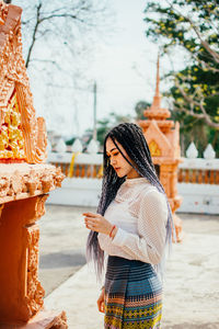 Young woman standing against built structure