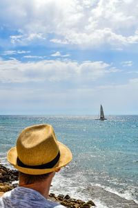 Rear view of hat on beach against sky