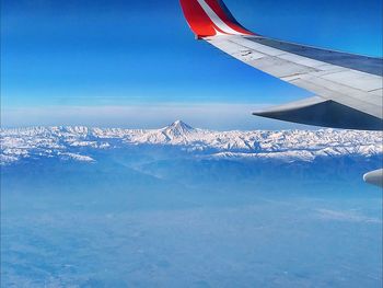 Aerial view of snowcapped mountains against blue sky