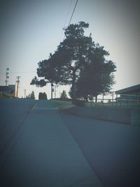 Empty road by trees against clear sky