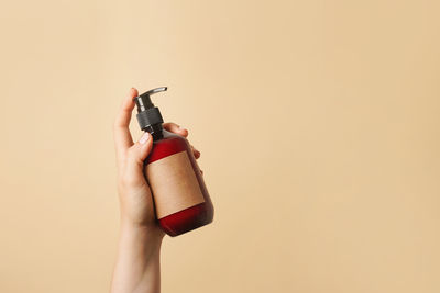 Close-up of hand holding bottle against white background