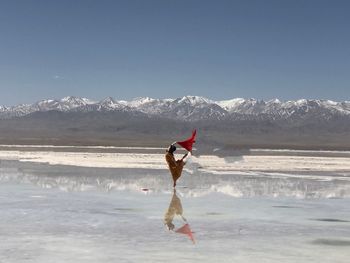 Full length of woman standing at beach against sky