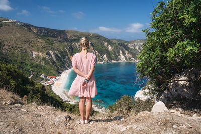 Rear view of woman standing on mountain against sky