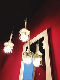 Low angle view of illuminated light bulbs hanging at night