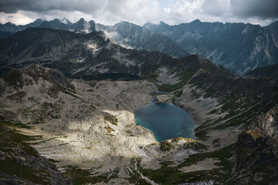 Scenic view of lake amidst mountains against cloudy sky