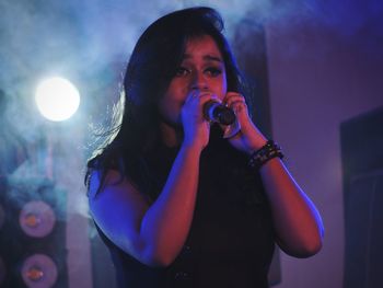Close-up of young woman singing on stage