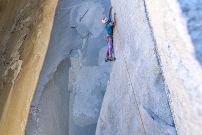 Rock climber looking down while climbing on big wall in yosemite