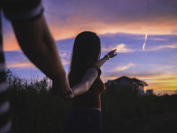 Silhouette woman holding camera against sky during sunset